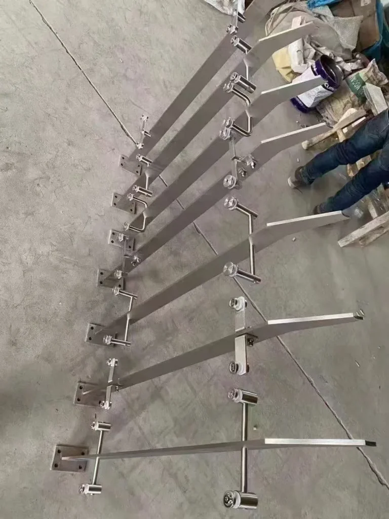 Flat-bar stainless steel railing posts with four-hole base plates arranged for inspection