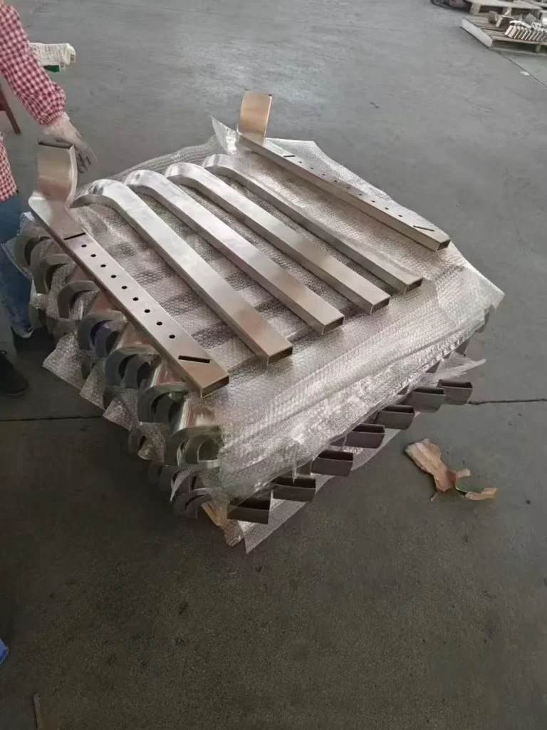 Fabricated square stainless steel railing posts arranged for material identity and dimensional inspection